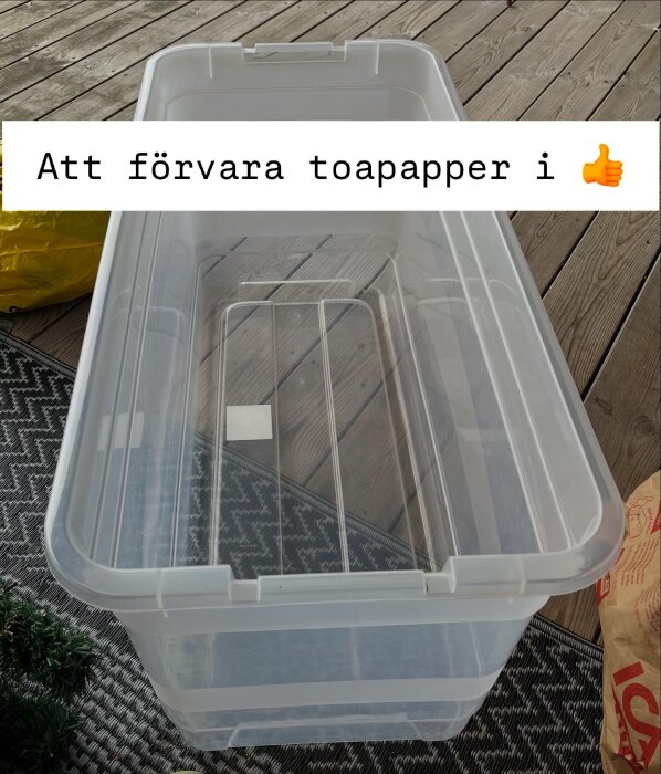 Genomskinlig plastlåda för förvaring av toalettpapper på trädäck, text med tummen upp: "Att förvara toapapper i 👍".