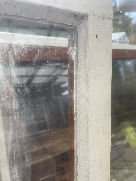 Närbild av ett fönster där glaset vilar i falsen, med kitt synligt längs kanterna, i fråga om monteringsmetod.