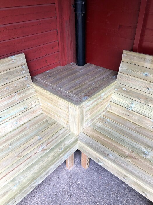 Träsoffa med lutande ryggstöd byggd för kyrkans personal, står mot en röd vägg.