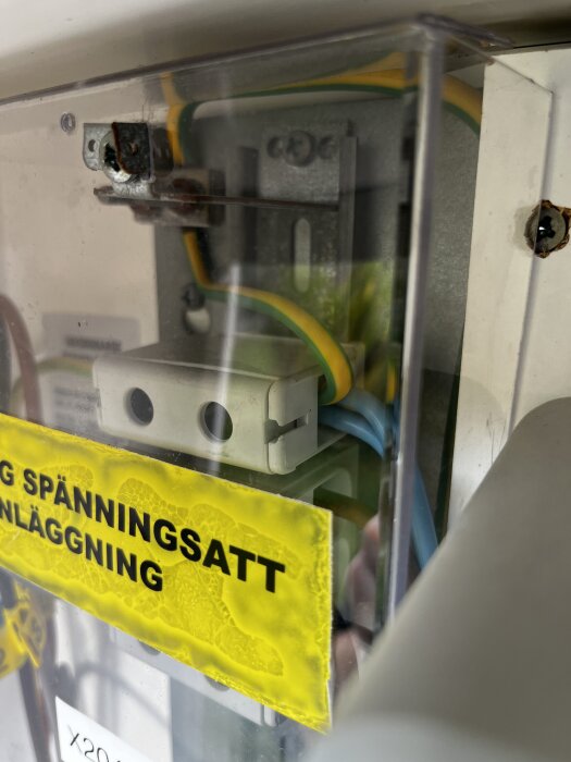 Elektrisk installation med kablar och ett varningsmärke i en genomskinlig box.