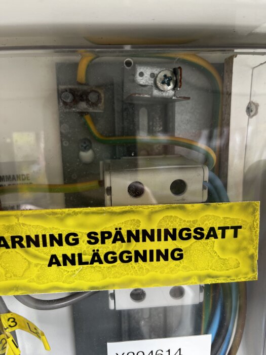 Elcentral med kablage och varningsskylt "Varning spänningssatt anläggning," som visar ledningsdragning i projekt.