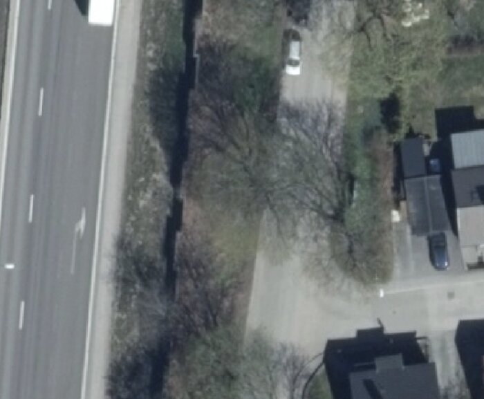 Flygbild över väg och omgivande grönska i ett bostadsområde vid Spettekaksvägen i Sköndal.