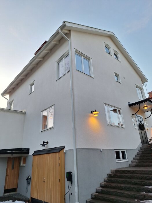 Vitputsad fasad av ett stort hus, nyputsad med kc bruk.