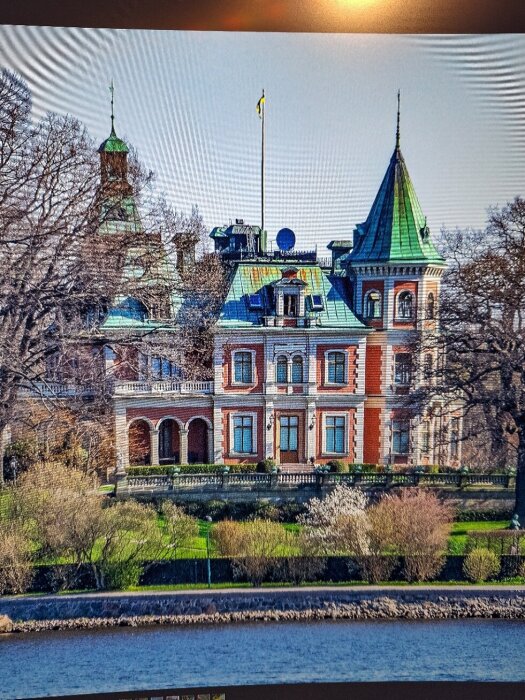 Stort herrgårdsliknande hus vid vatten med gröna tak i parkmiljö, nämnt som putsat Wallenbergs presentationshus.