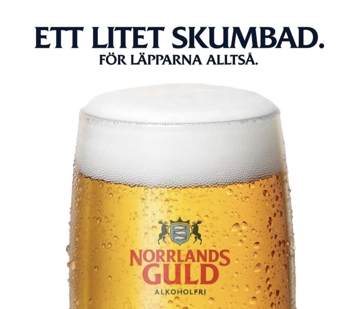 Alkoholfri öl Norrlands Guld i glas med skumkrona, text ovan: "Ett litet skumbad. För läpparna alltså.