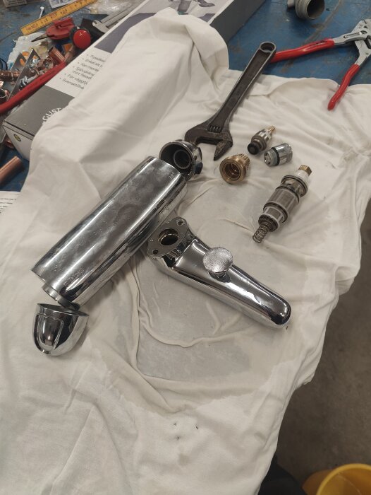 Isärmonterad FMM 9000 badkarsblandare med delar och verktyg på duk i verkstadsmiljö.