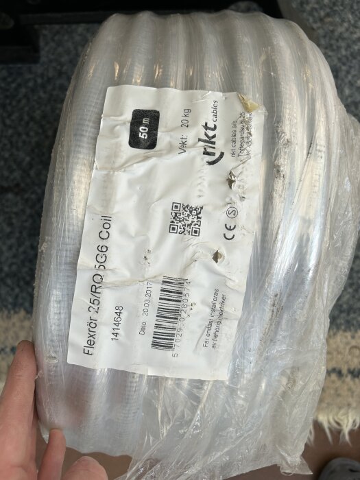 Rulle med NKT färdigdragen slang, etikett visar "50m", vikt och QR-kod. Används för fasadskåp, central eller värmepump.