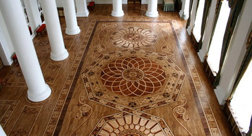 Dekorativt trägolv med intrikata mönster som påminner om palats, omgivet av vita kolonner och stora fönster.