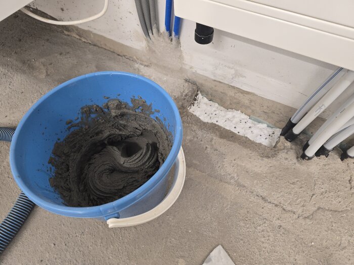 Hink med murbruk bredvid vägg med frigolit och rör.