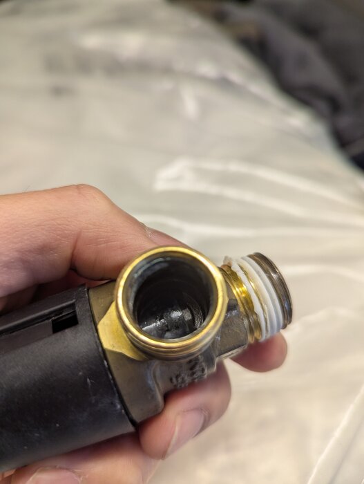 Närbild av en säkerhetsventil för varmvattenberedare, hållen i en hand. Ventilen har ersatts efter att ha läckt.