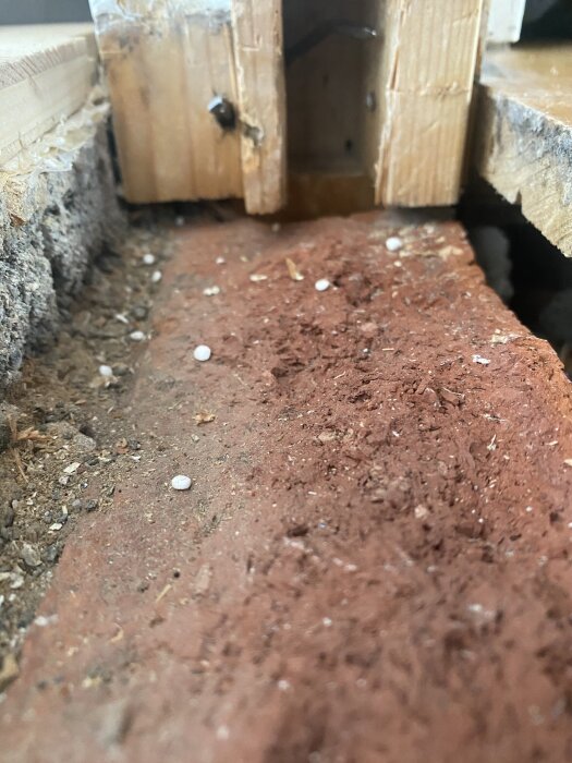 Närbild av en nedre del av dörrkarm med ojämna tegelstenar och träreglar, relaterat till byte av tröskel.