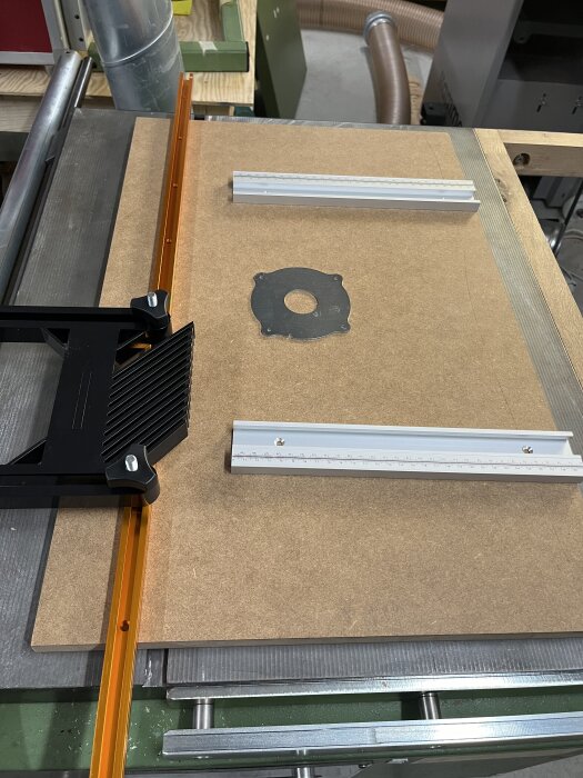Fräsbord under konstruktion med mdf-skiva, t-spårprofil och anhåll placerade för bordsbreddning.