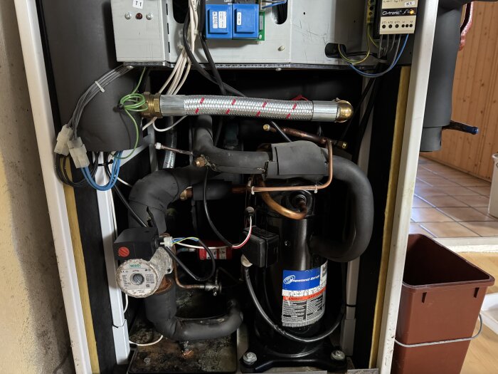 Inre del av värmepumpen Thermia Diplomat med kablar, rör och pump synliga.