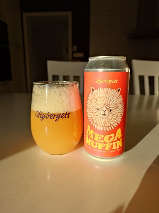 Ett glas och en burk Stigbergets Mega Muffin IPA på ett bord i solljus.