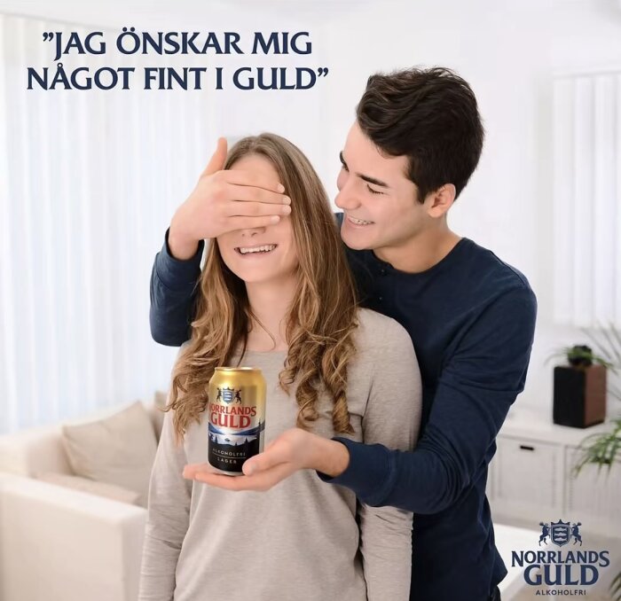 Man överraskar kvinna med en burk Norrlands Guld alkoholfri öl, hon ler medan han täcker hennes ögon.