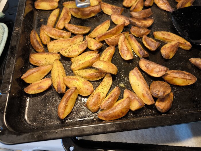 Hemlagad klyftpotatis kryddad med dill och persillade på en ugnsplåt.