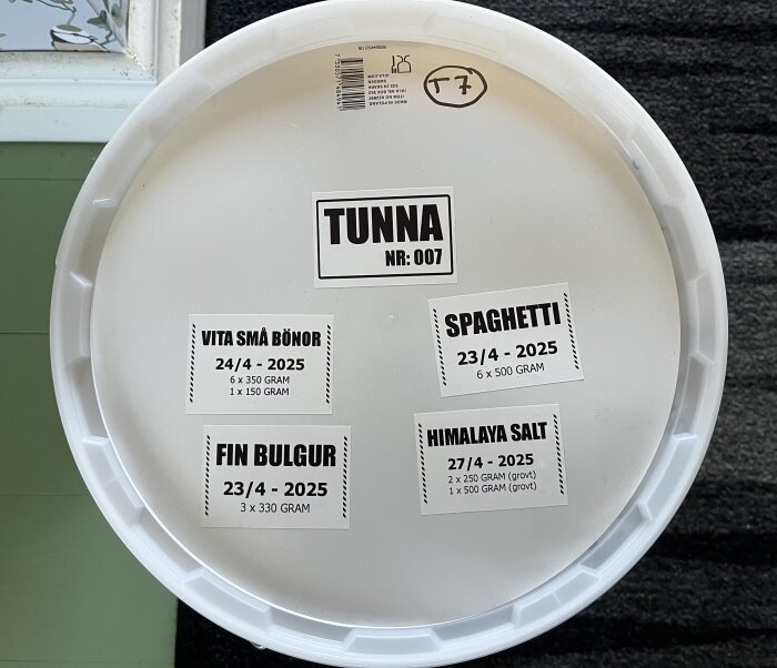 Vit plasttunna med etikett "TUNNA NR: 007". Märken visar innehåll som vita små bönor, spaghetti, himalayasalt, fin bulgur och deras mängder.