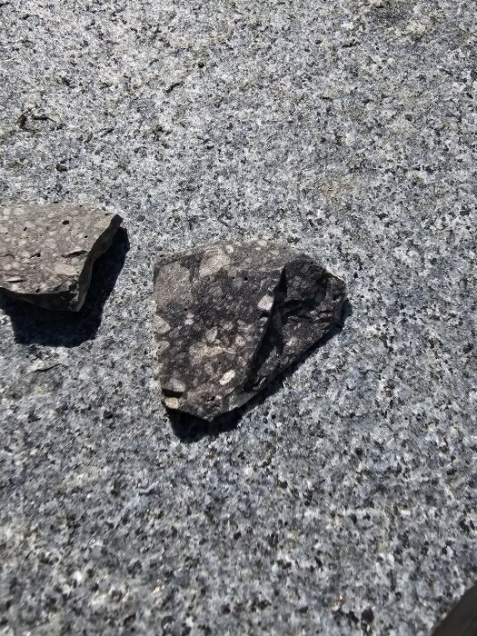 Stenplattor med grov yta, möjligen granit, ligger på betonggolv. Bilden relaterar till diskussion om avloppsläcka och material under golvet.