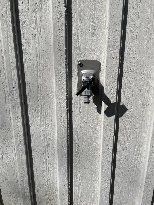 Utkastare monterad på vit, vertikalt panelad vägg.