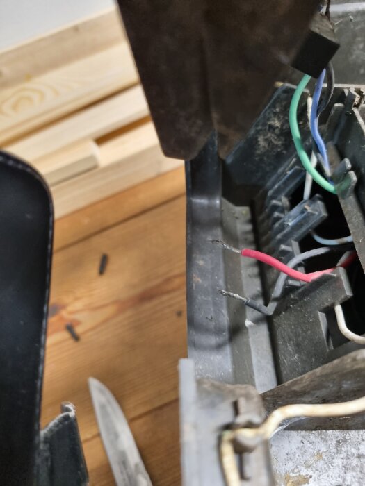 Brutna röda och svarta sladdar i ladduttag på en Husqvarna 305 från 2017, med exponerade stift och andra färgade sladdar synliga.