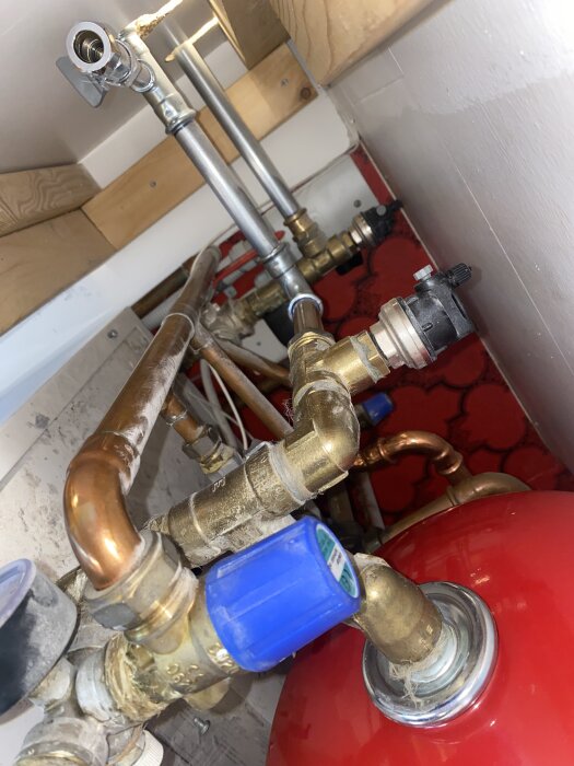 Rör och ventiler till bergvärmepump med blå ventil och kopparrör i närbild, relaterat till lågt tryck i golvvärmesystem.