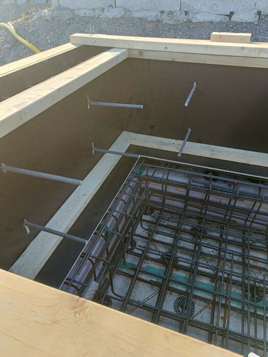 Form för betonggjutning med träbalkar och armeringsjärn, provisoriskt upphängda, i byggprojekt.