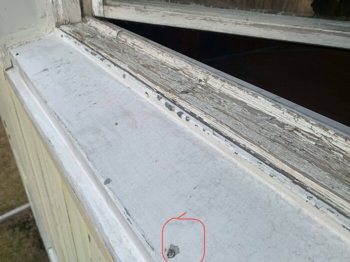 Fönsterbleck med dåligt fäste och slitna träytor, där en infästning är markerad med röd cirkel för att illustrera problemområdet.