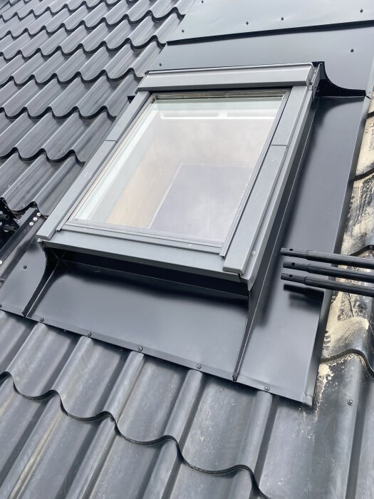 Takfönster med ny plåtinstallation på svart tak, fokuserar på ovan- och underbeslag för att förhindra läckage.