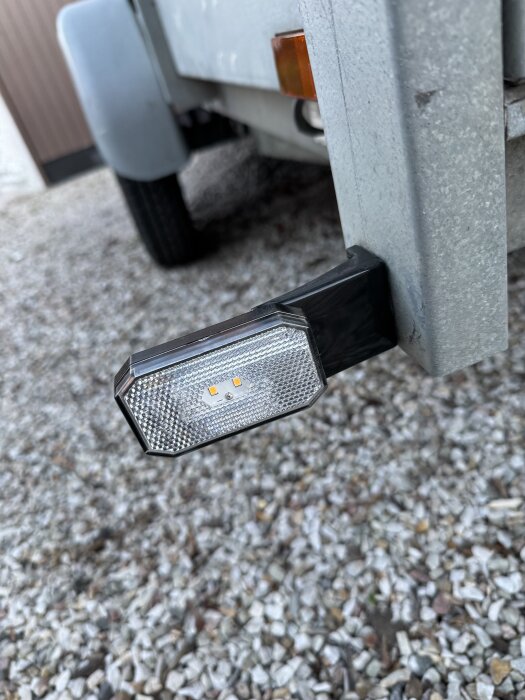 Nyinstallerat positionsljus på ett släp, monterat på metallram, fotograferat mot en bakgrund av grus.