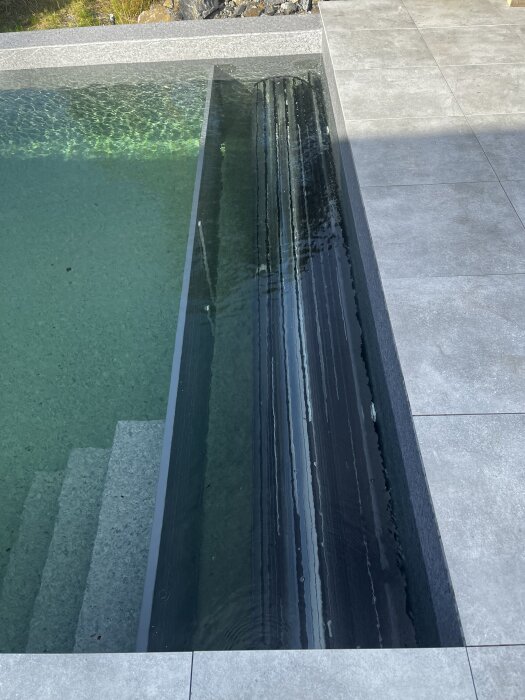 Ihoprullade lameller för pooltäcke ligger i poolen, redo för montering under soligt väder.