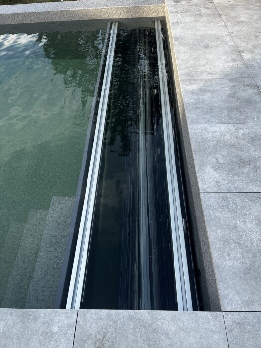 Ihorullade lameller vid en pool, redo för montering av skyddstäcke efter bättre väder.