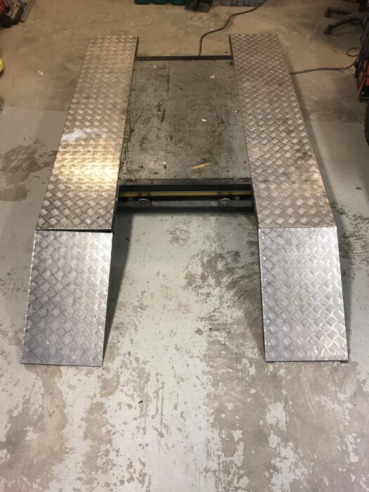 Modifierat lyftbord med breddning av metall för ATVer i garage.