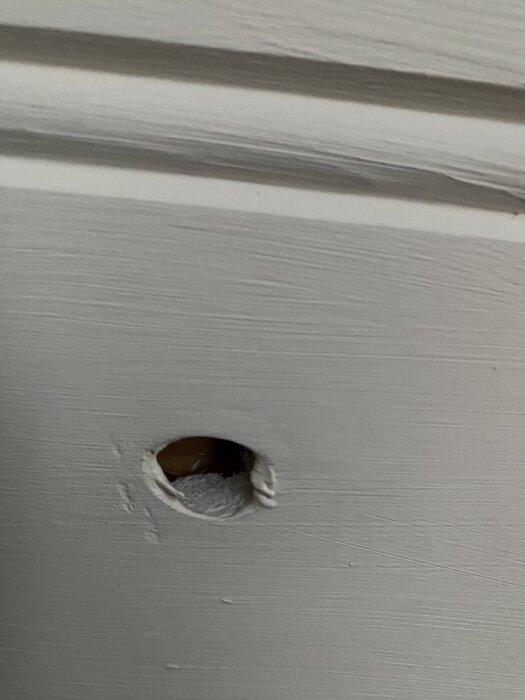 Hål i vitt tak med ojämna kanter, potentiellt orsakat av slitage eller skada, i ett hus byggt 2010.