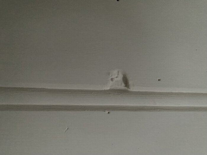 Hål i innertak, vitmålat, med skador och märken synliga. Byggnad från 2010.