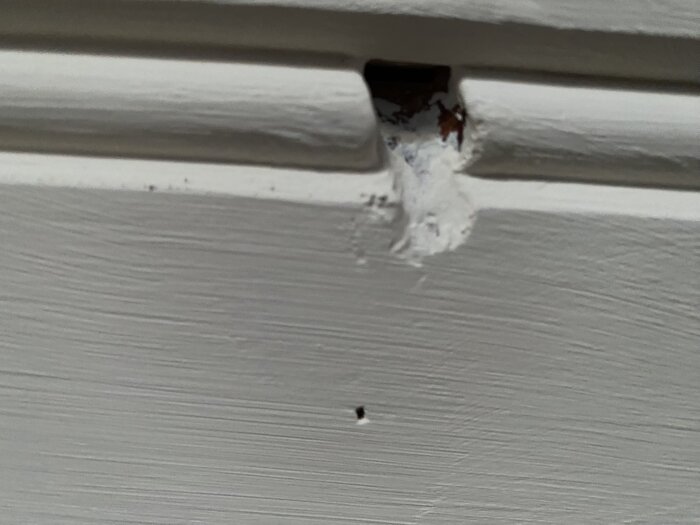 Hål i vitt innertak med ojämna kanter, potentiellt skadat.