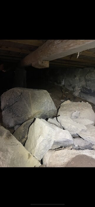 Stenar under gammalt hus, en del kollapsade, bildar grunden för timmerhus från 1890. Synligt bärlinestöd saknas delvis.