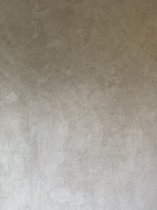 Gipsputsad vägg med ojämn och grov yta, önskat sidenmatt och slätt resultat, renovering pågår med dammbindning.