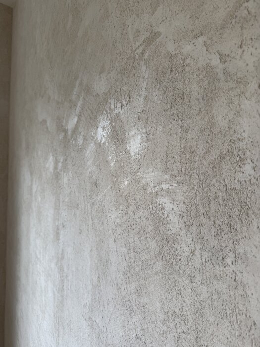 Vägg med ojämn yta där gipsputs har applicerats men resultatet är skrovligt istället för slätt och sidenmatt.