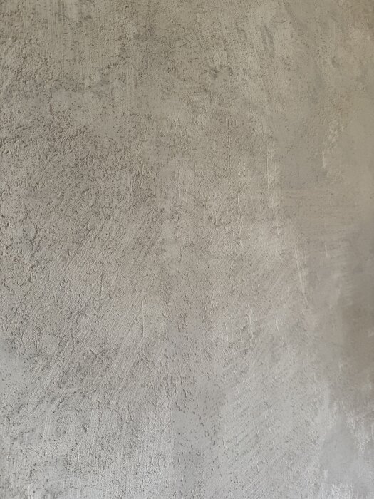 En vägg med ojämn gipsputs, där ytan är skrovlig med några små partier av blankare finish.