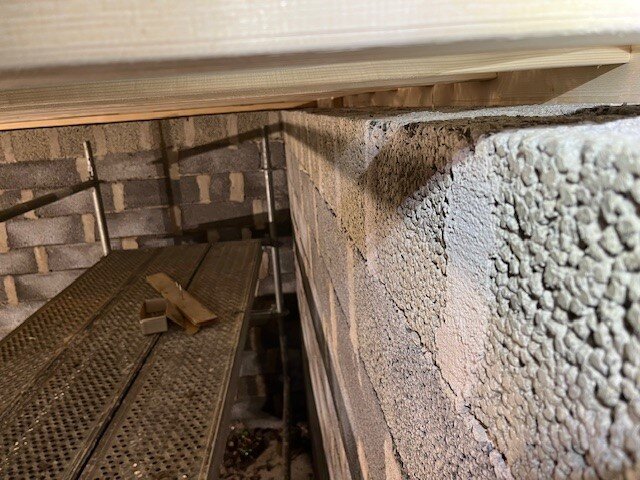 Murad vägg med synlig luftspalt på 4 cm mellan väggen och innertaket i ett garageprojekt. Byggställning står intill väggen.