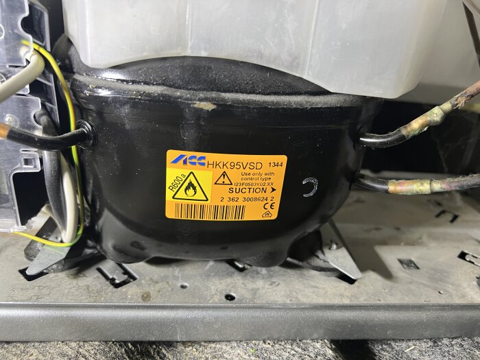 Fryskompressor med etikett "R600a", omgiven av kablar. Potentiellt fel del av inlägg om frysproblem och felsökning.