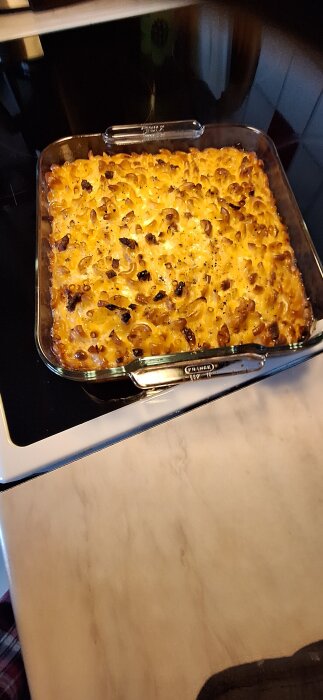 Makaronpudding i en ugnsform, nylagad och gyllenbrun, stÄr pÄ en spis redo att serveras.