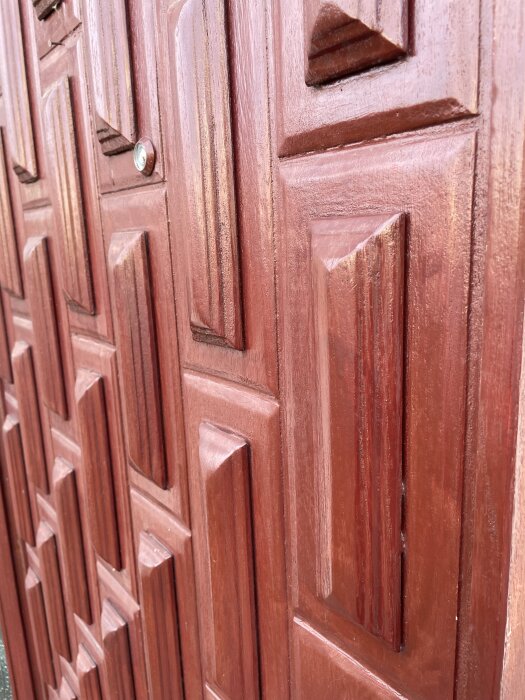 Dörr med träpaneler och utsmyckade mönster, där frågan gäller infästning av dekorationerna.