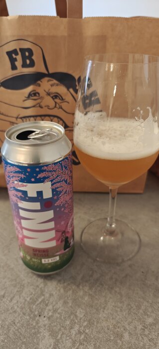Burk och glas med öl, märkt "Spring Weisse" på burken med en illustration av blommande träd på etiketten.