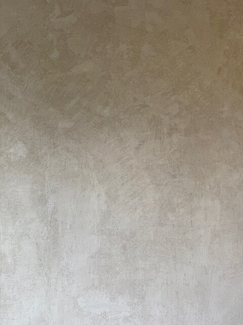 En vägg med ojämnt applicerad gipsputs där ytan ser skrovlig ut med små områden av blankare finish.