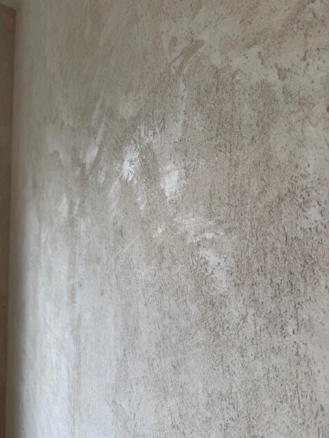 Ojämn väggyta med gipsputs syns i nära bild, ytan är skrovlig och inte helt slät som önskat.