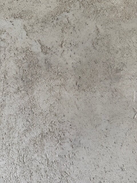 En vägg täckt med ojämn gipsputs, visar ett skrovligt och grovt utseende med små släta områden. Resultatet är inte som önskat sidenmatt och slätt.