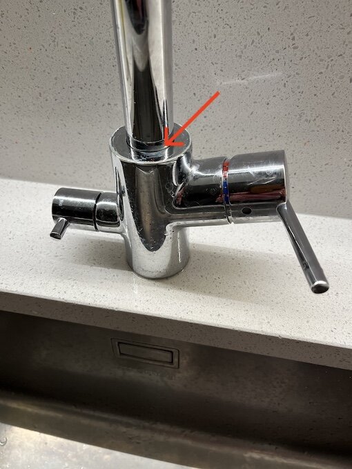 Hans Grohe köksblandare på diskbänk med en läcka vid röd pilmarkering.