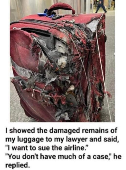 En röd resväska med allvarliga skador, trasigt tyg och utsatta innandömen, står på en golvyta.