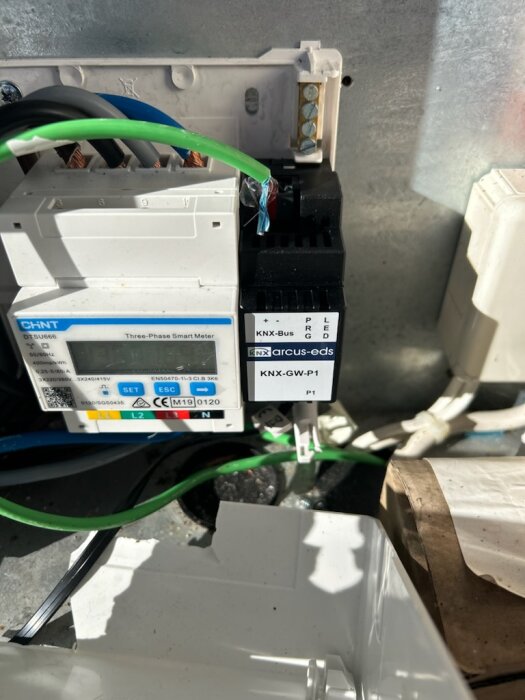 Bild på en CHNT DT SU666 tre-fas elmätare med installerad KNX-GW-P1 HAN-gateway, kablar är anslutna för dataöverföring.